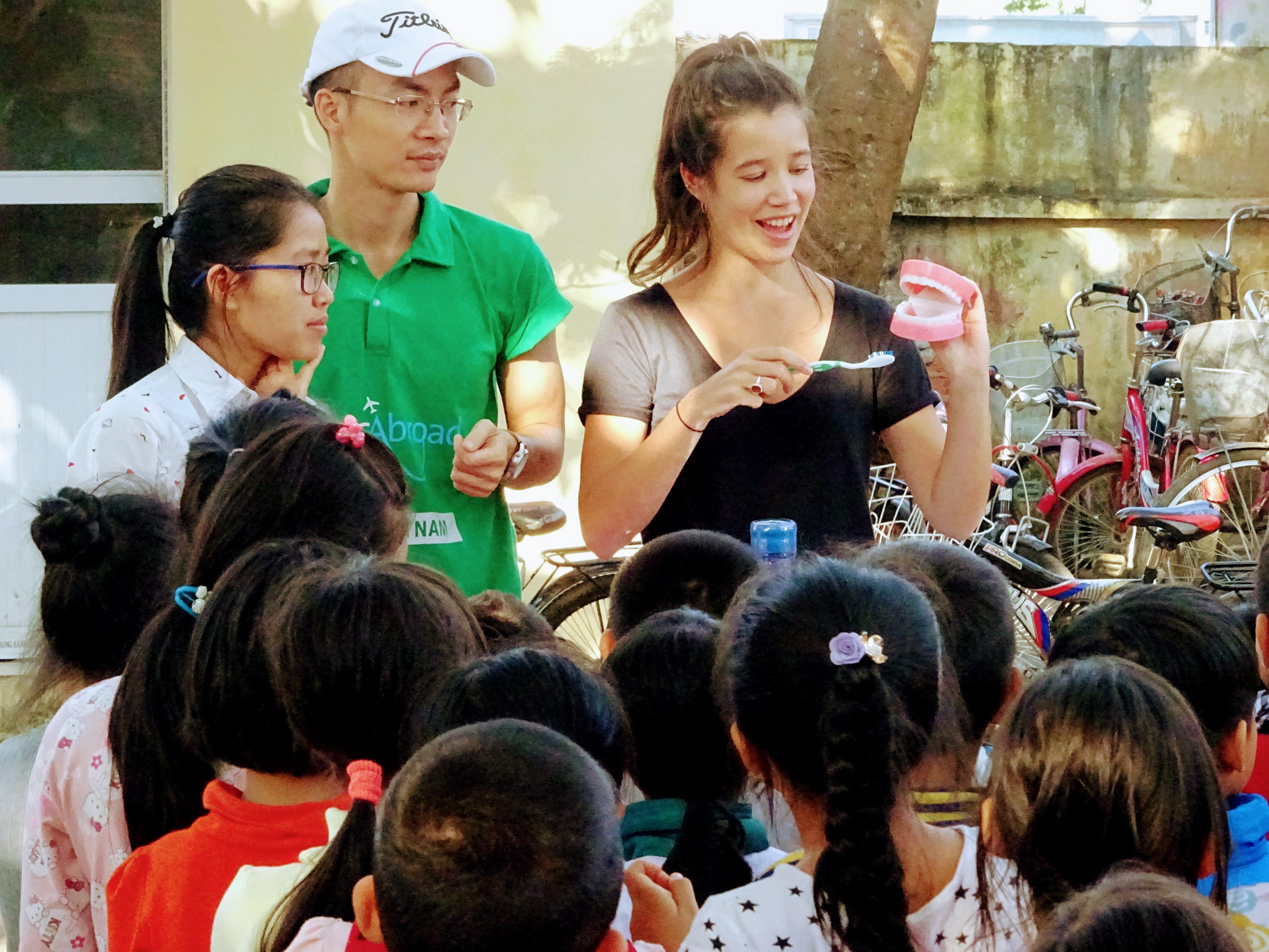 Projects Abroad volunteer working with children in Vietnam demonstrates how to brush your teeth at a Childcare placement. A group of Childcare volunteers teach a group of children how to brush their teeth at a care centre in Vietnam.